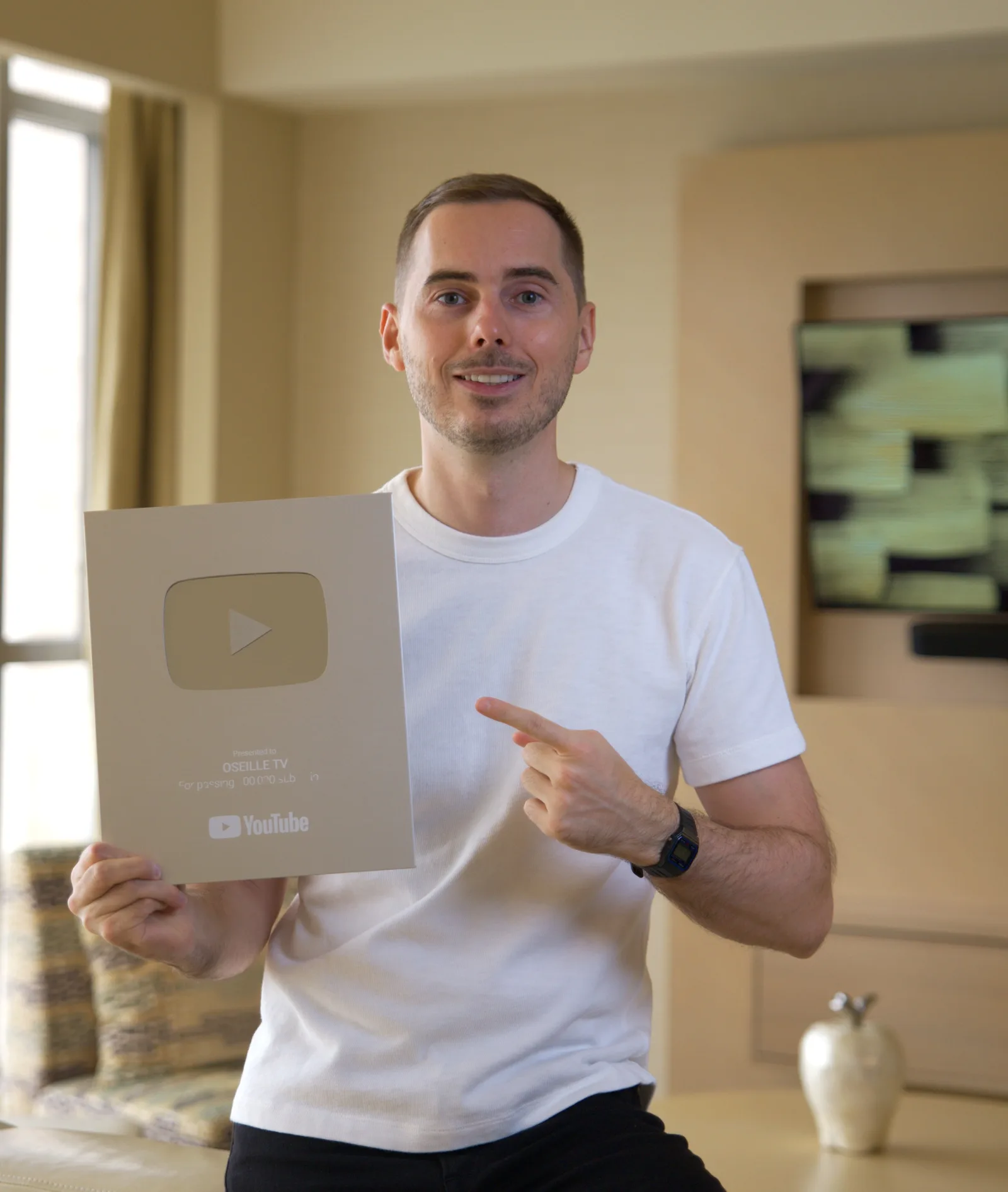 Julien, fondateur d'Oseille TV, tenant son trophée YouTube (plaque de créateur).
